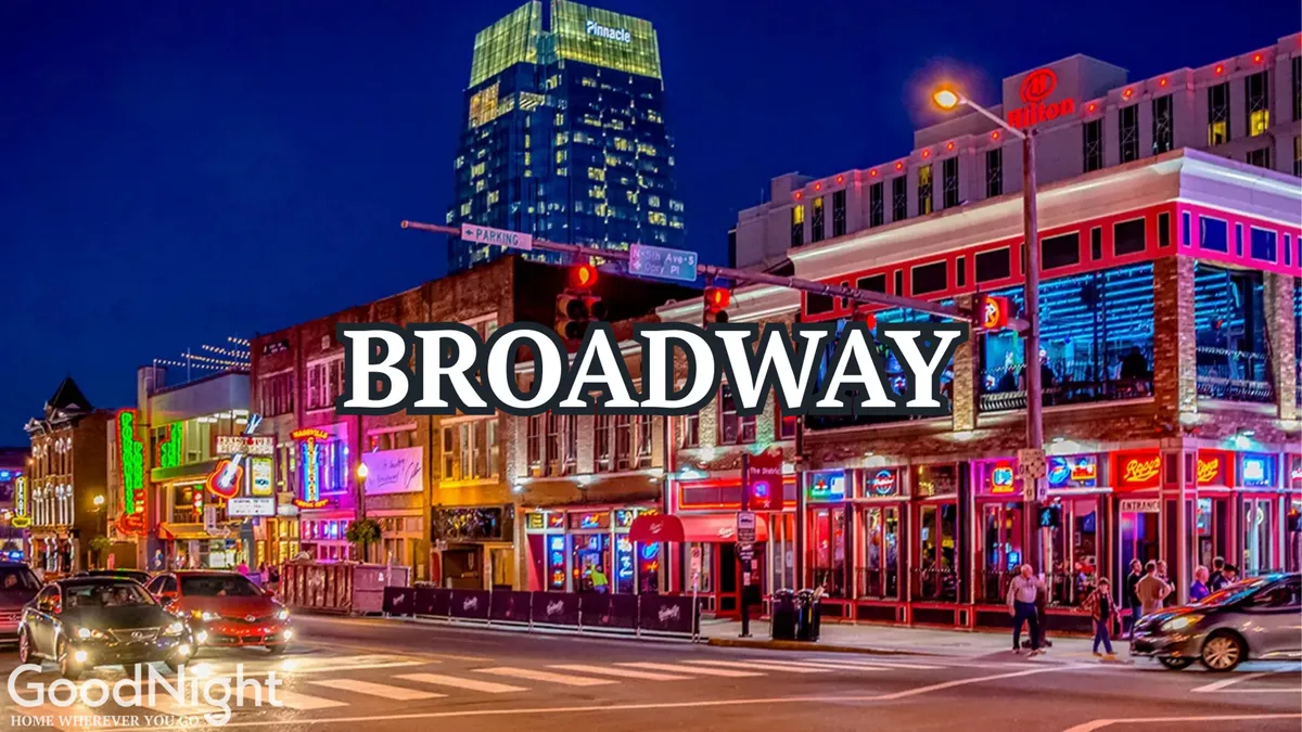 A lively nighttime streetscape featuring neon signs, bustling crowds, and nightlife activity set against Nashville’s high-rise backdrop. The energy radiates from the illuminated venues lining the busy street, capturing the pulse of the city’s after-dark scene.